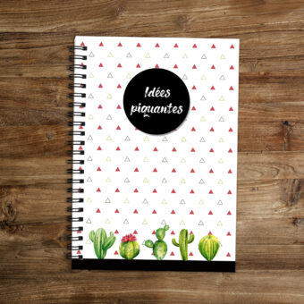 Carnet de notes A5 avec reliure en spirale métallique noire. Le fond est parsemé de petits triangles sur lequels un cercle disque noir indique "idées piquantes" et agrémenté en bas d'une frise de petits cactus.