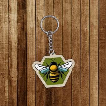 Porte-clés en bois décoré d'une abeille sur un fond hexagonal vert.